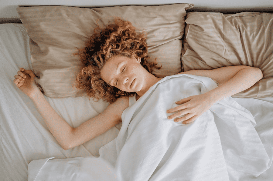 Curley haired woman in a restful sleep, in a bed